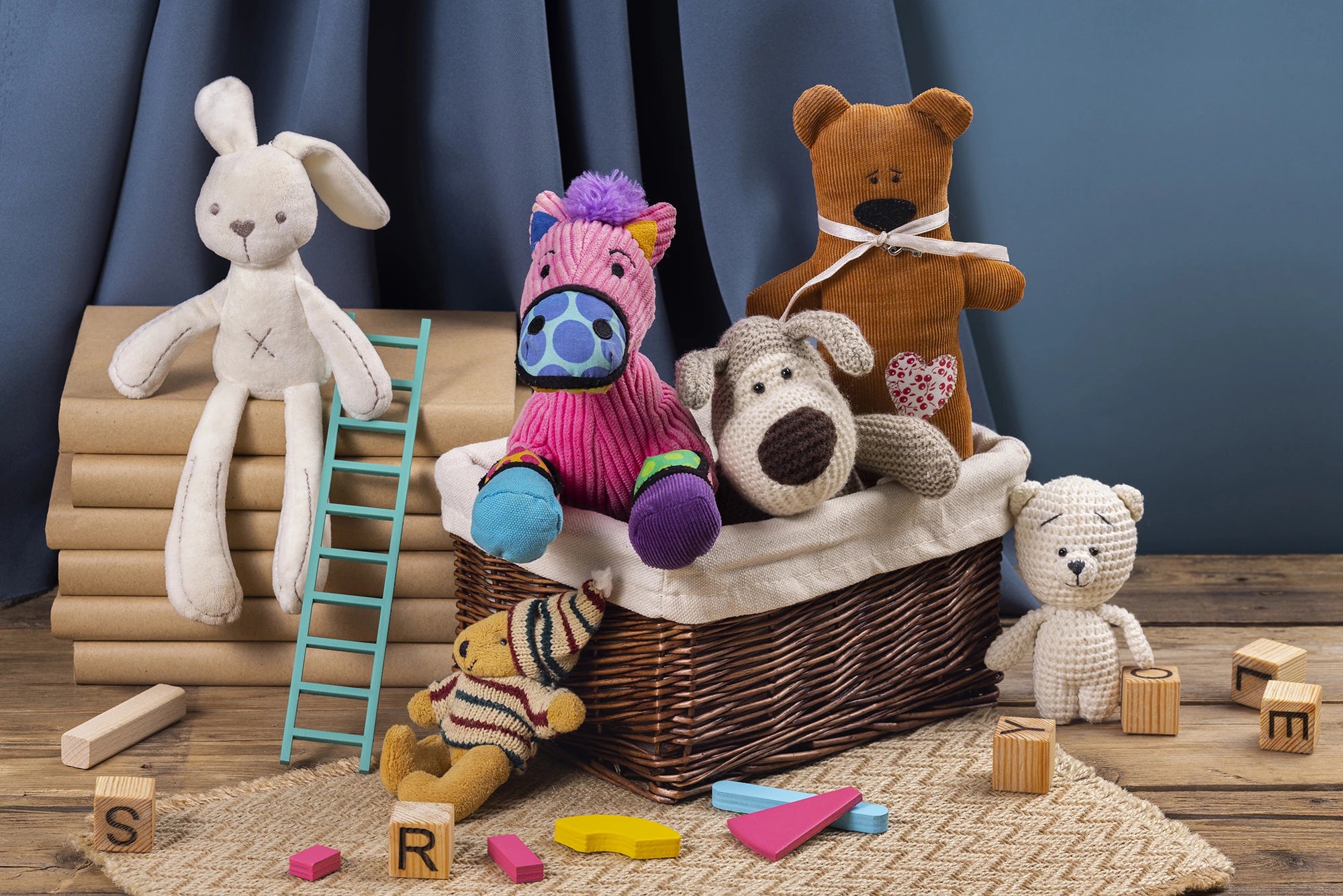 Collection of stuffed animals in a basket with toys around on a wooden floor.