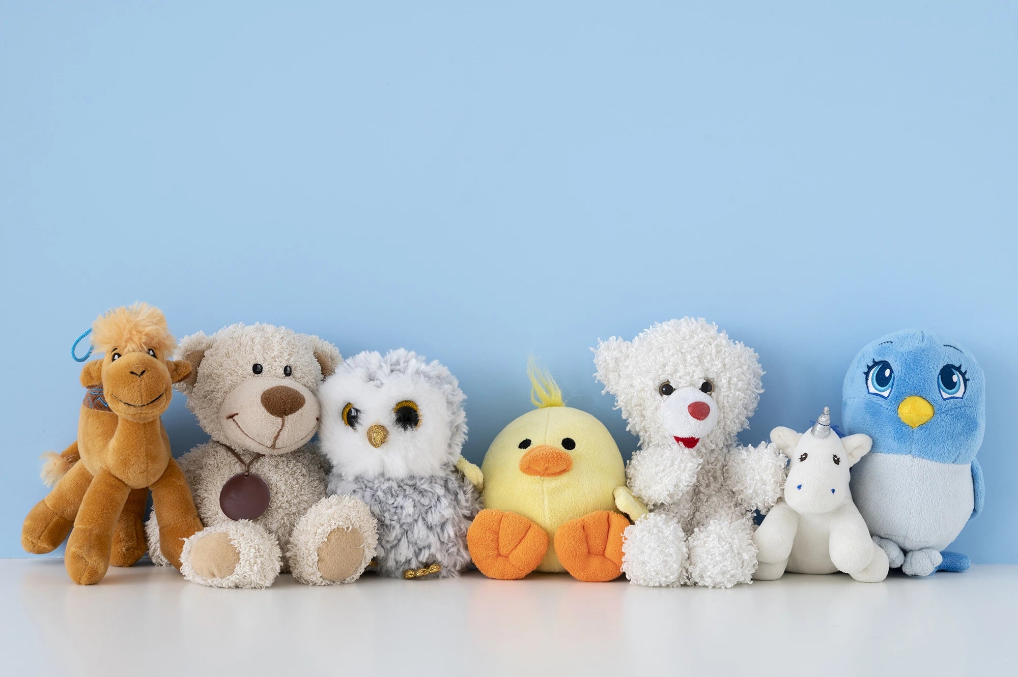 Row of colorful stuffed animals against a light blue background